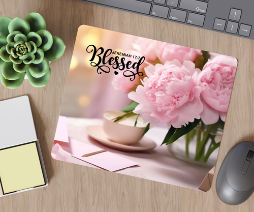 Desk setup with a floral mouse pad featuring pink flowers and a cup, on a wooden surface.