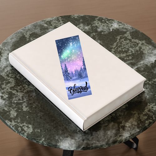 Book with a bookmark featuring a snowy landscape and 'Blessed' text on a marble surface.