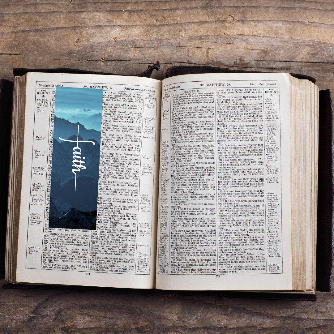 Open book with a mountain scene and the word 'Faith' on a wooden surface