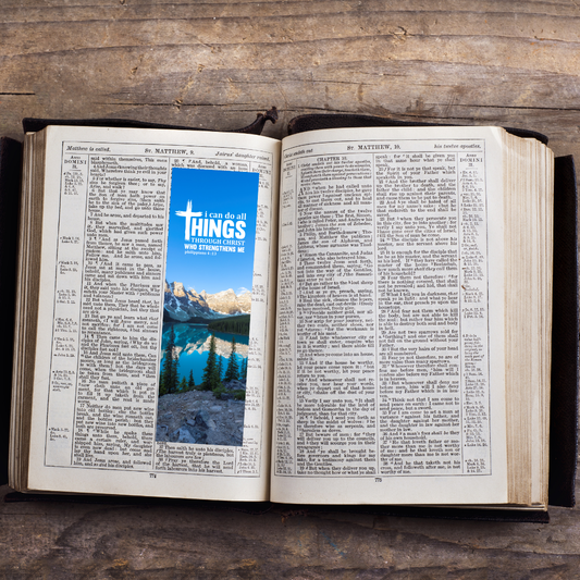 Open book with a scenic image and 'I can do all things' text overlay on a wooden surface