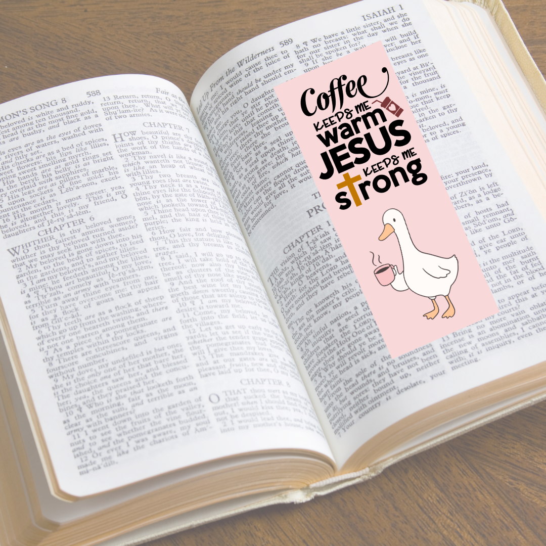 Open book with a pink bookmark featuring text and a duck illustration on a wooden surface.